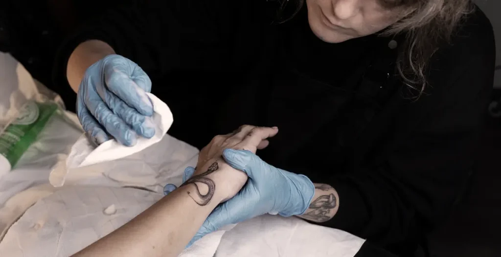 A lady applying tattoo aftercare on a fresh tattoo